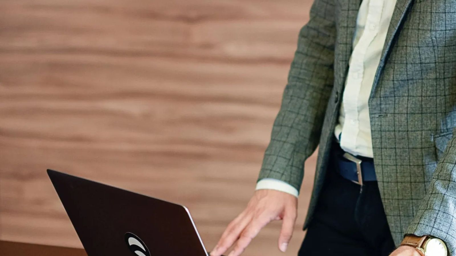 Gestor organizando tarefas no laptop em mesa de reunião